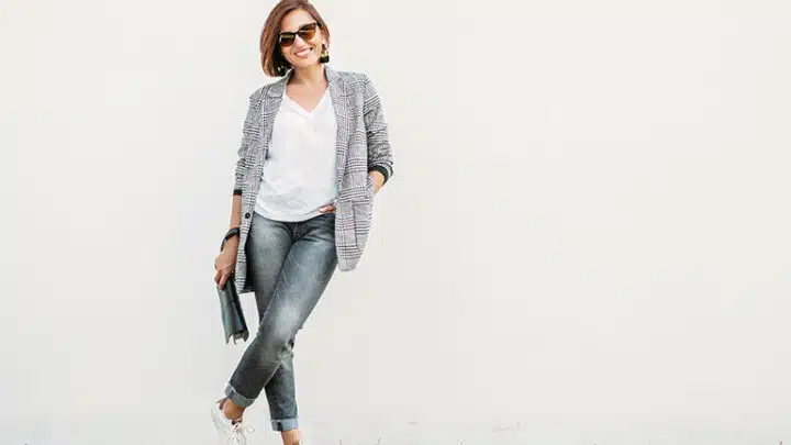 Stylish woman standing in front of grey background.