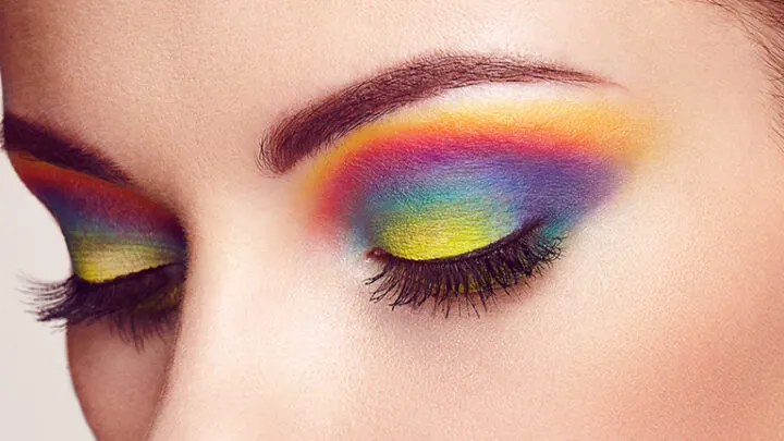 Close up of woman with rainbow eyeshadow, one of our summer makeup trends.