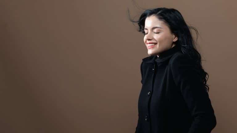 Woman smiling wearing a trendy coat.
