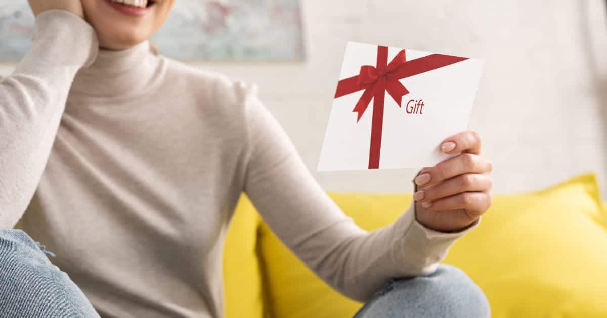 Woman sitting inside holds gift card.