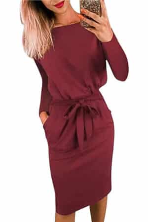 Close-up of model wearing burgundy long-sleeved dress with belted waist.