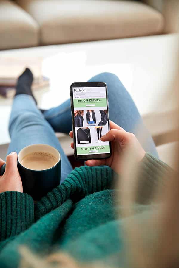 Clothing Inflation: 6 Ways to Stay Stylish as Prices Rise 2 Close up of woman shopping clothes online with her smartphone.