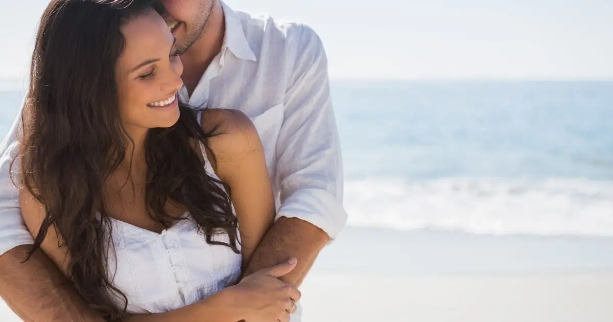 Couple embrace on beach.