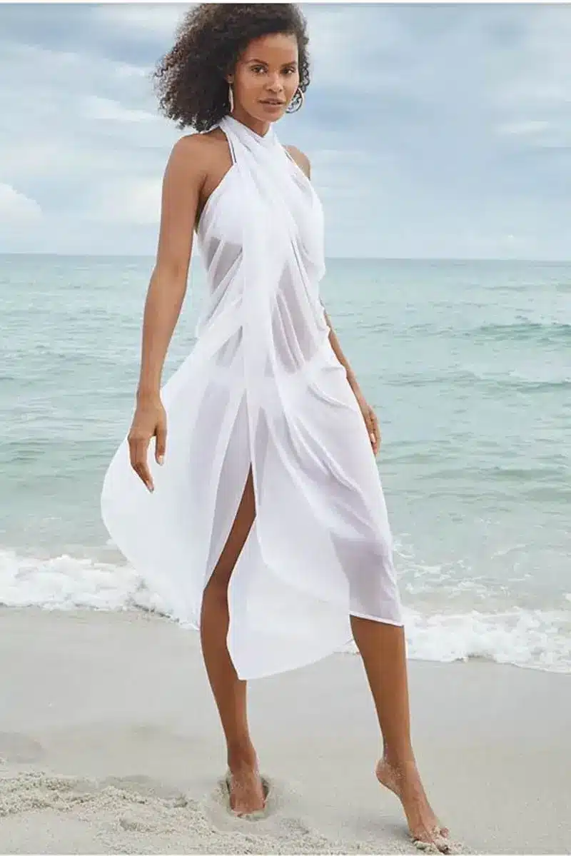 Woman on beach wearing gauzy white swim coverup.