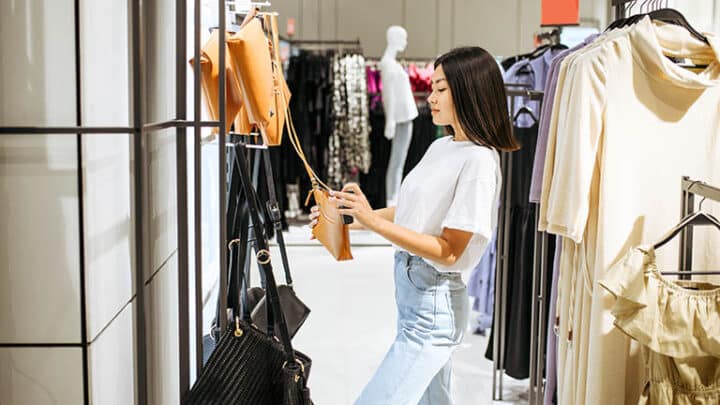 Woman obsessed with purses holds handbag in designer boutique.