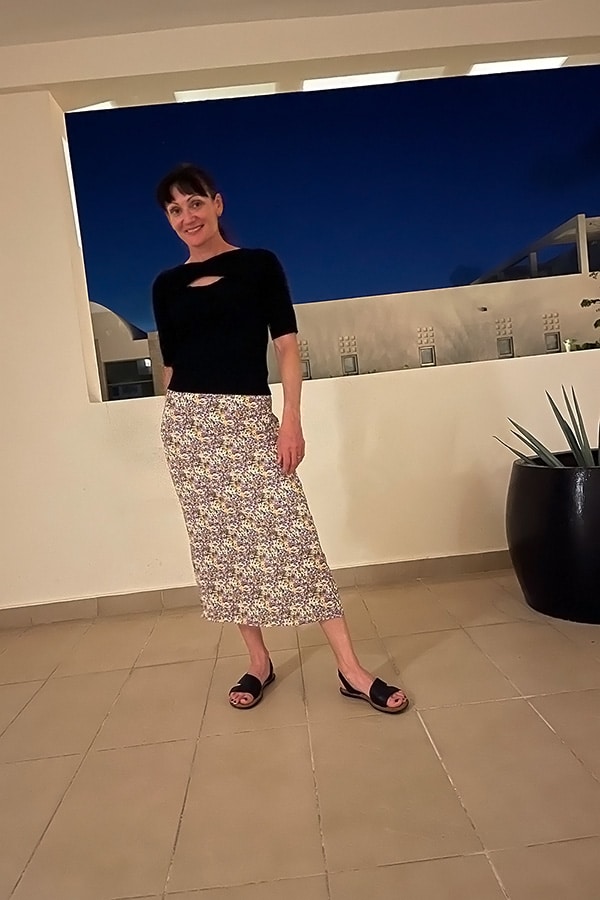 Catherine Brock standing outside at night, wearing black knit top and floral skirt from Chicwish.