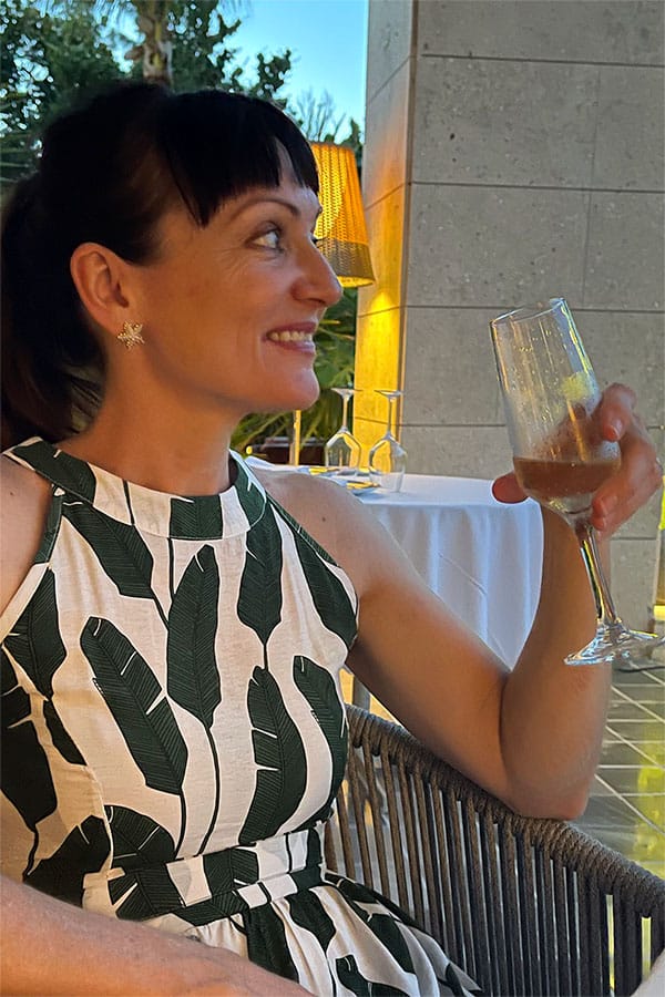 Close-up of Catherine Brock wearing starfish earrings while holding a glass of champagne.