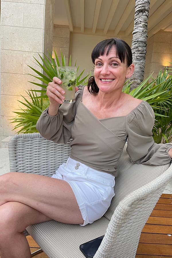 Honest Chicwish Review (and Photos!) After Spending $600+ 7 Catherine Brock sits outside in wicker chair wearing beige wrap-style top from Chicwish.