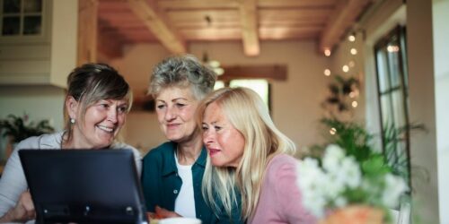 Three stylish senior woman smile while shopping online together.