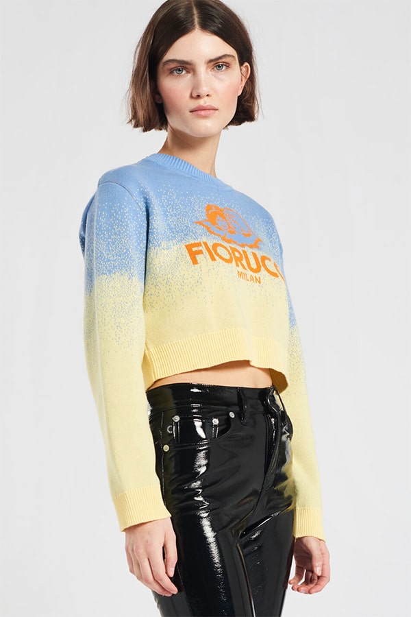 Model wearing short Fiorucci logo sweater with vinyl pants.