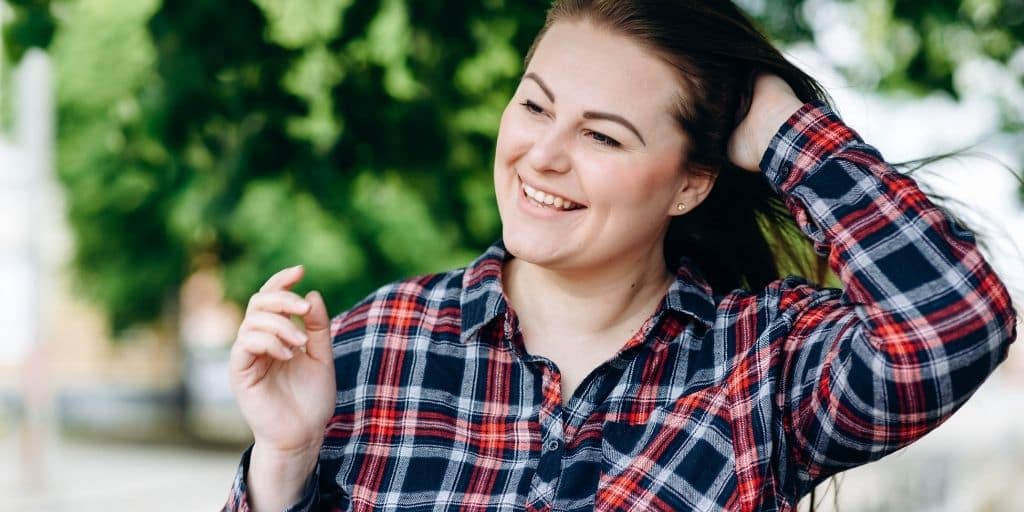 Smiling, confident person runs hand through her hair.