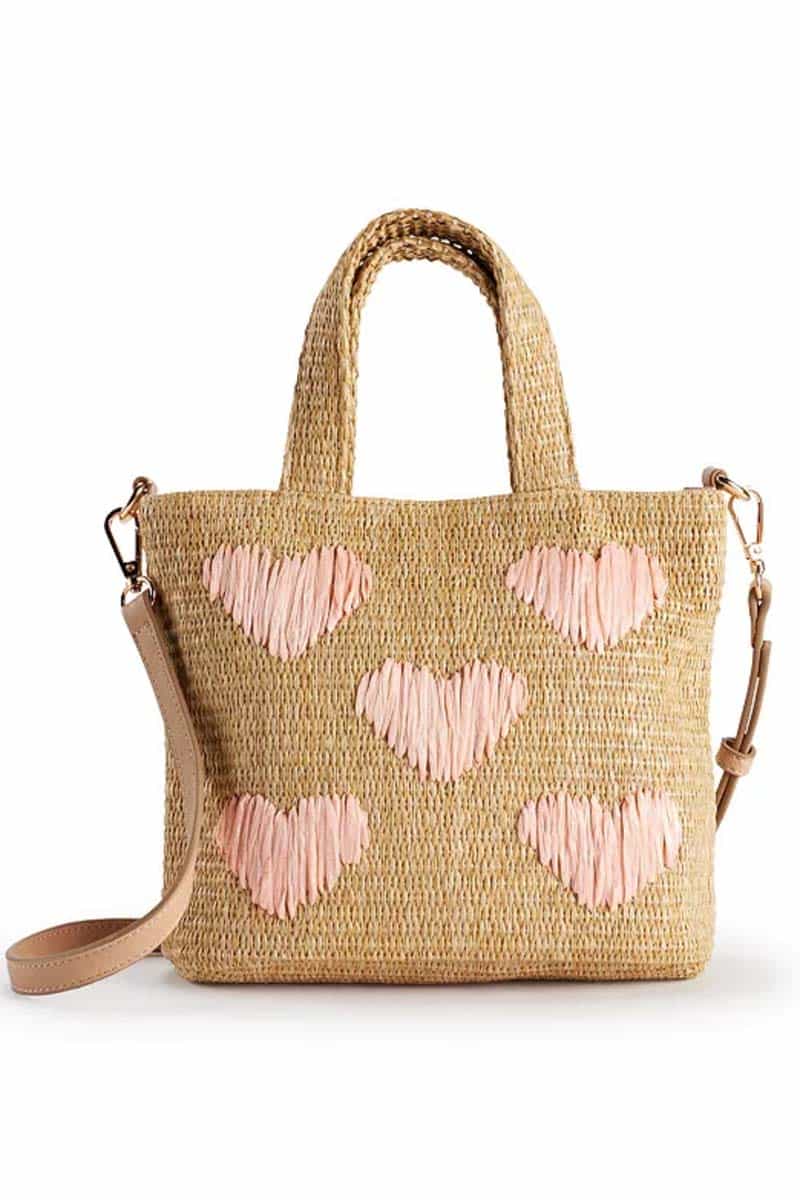 Product shot of a woven crossbody bag with pink hearts.