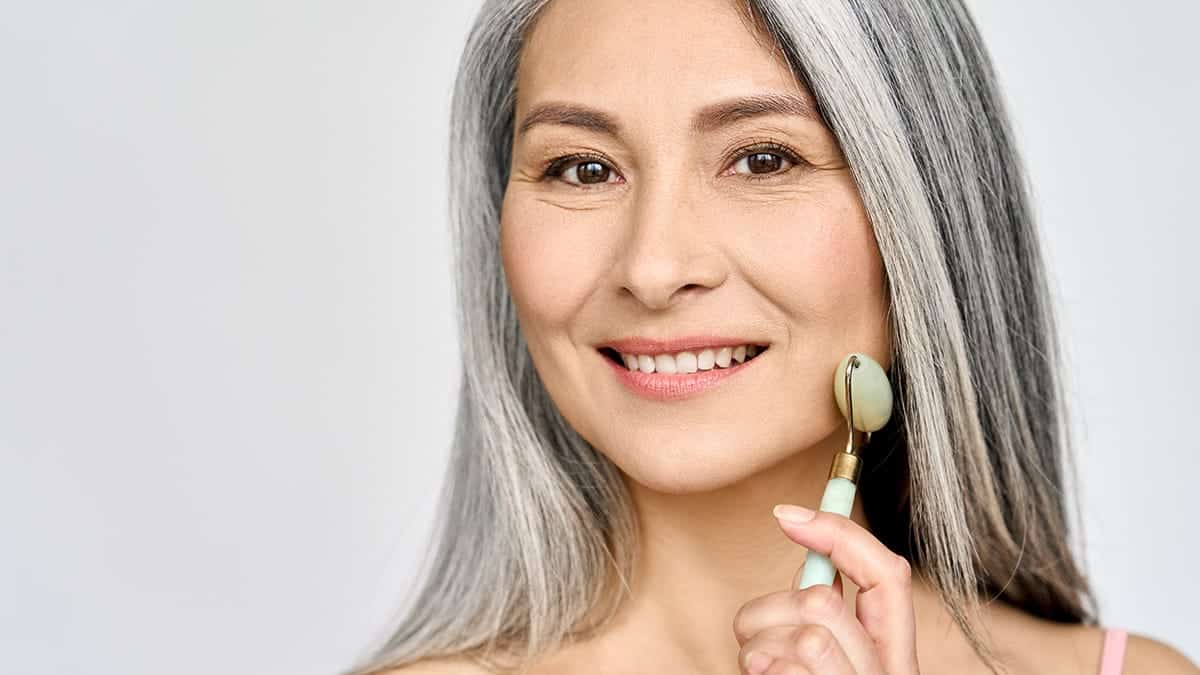 Smiling woman uses jade roller.