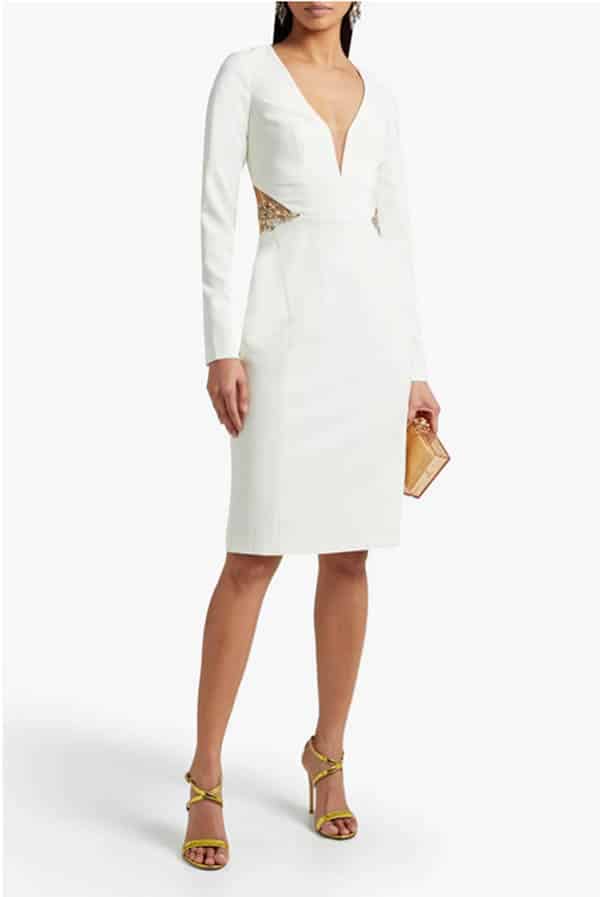 Model wears white dress with sheer panels. 