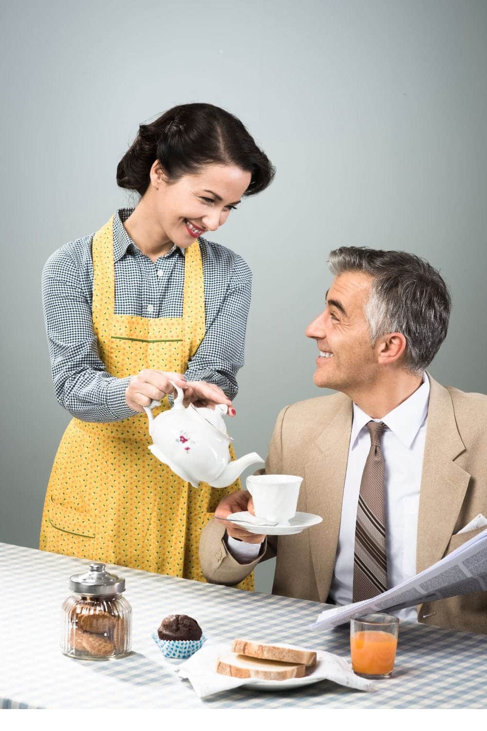 Smiling woman pours tea for man wearing suit.