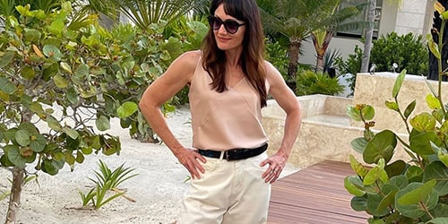 Catherine Brock stands outside wearing fashionable jeans and tank top.