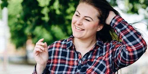 Fashionable woman smiles while standing outside. 