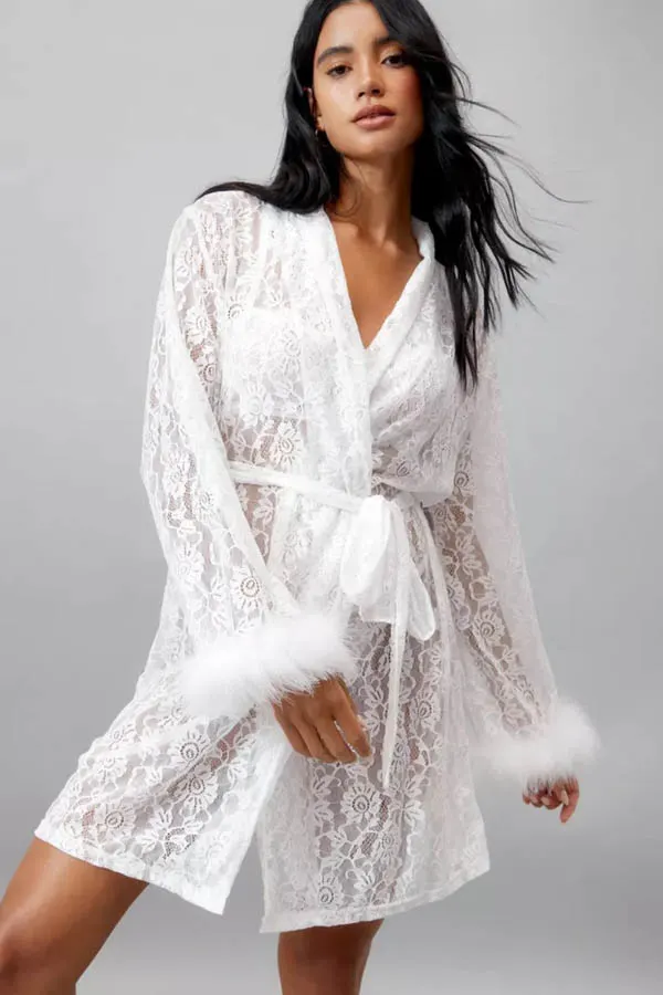 Model wears midi length robe with feather trim. 