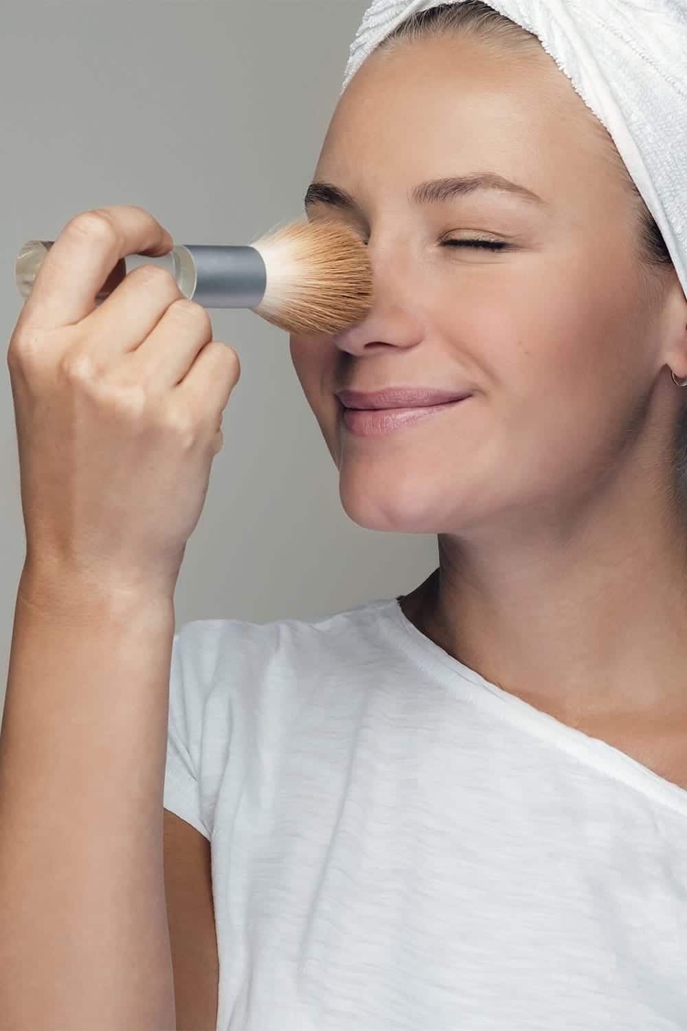Woman applies powder to her face.