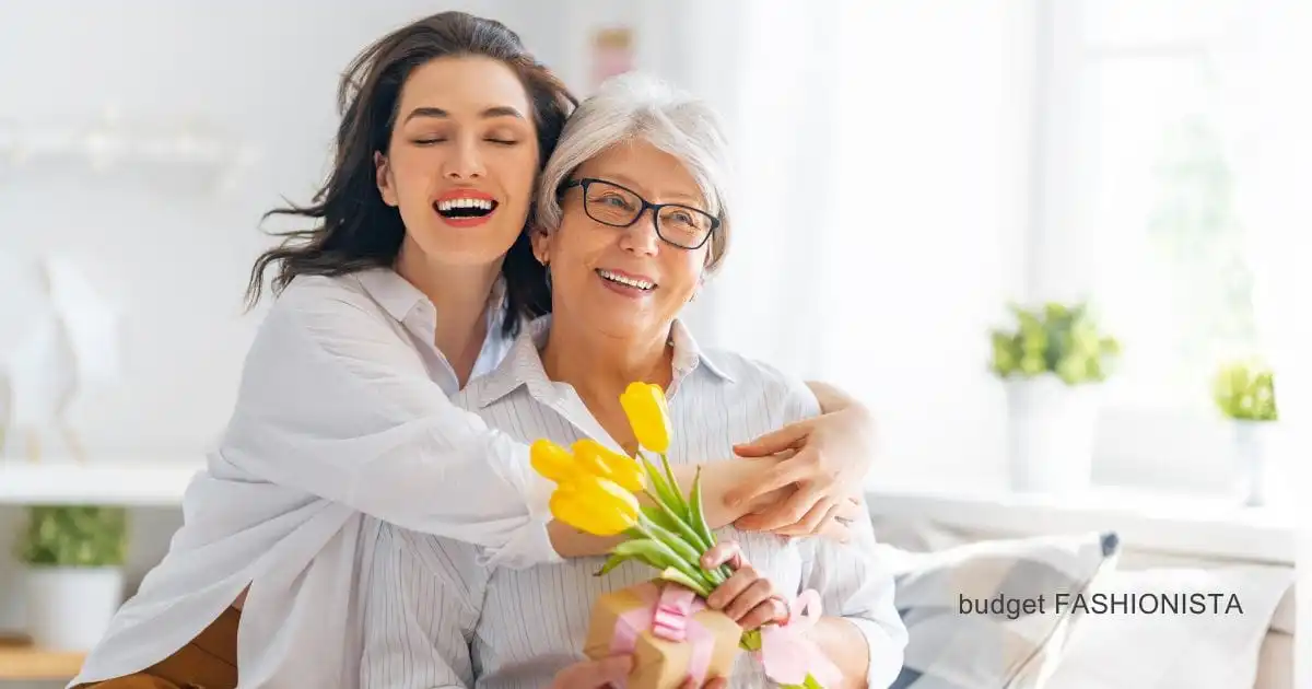 Woman embraces mom with flowers in kitchen.