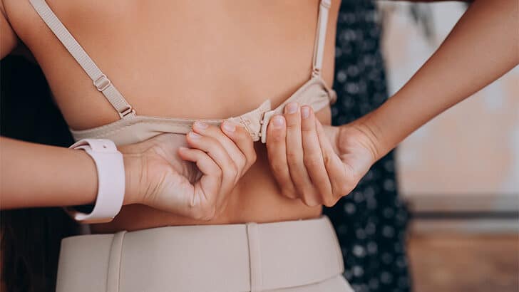 Rear view of woman taking off her bra as a concept for where to buy bras online.