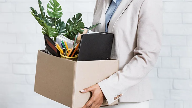 Frau trägt nach ihrer Entlassung eine Kiste mit persönlichen Gegenständen aus dem Büro, um sich auf eine Rezession vorzubereiten.