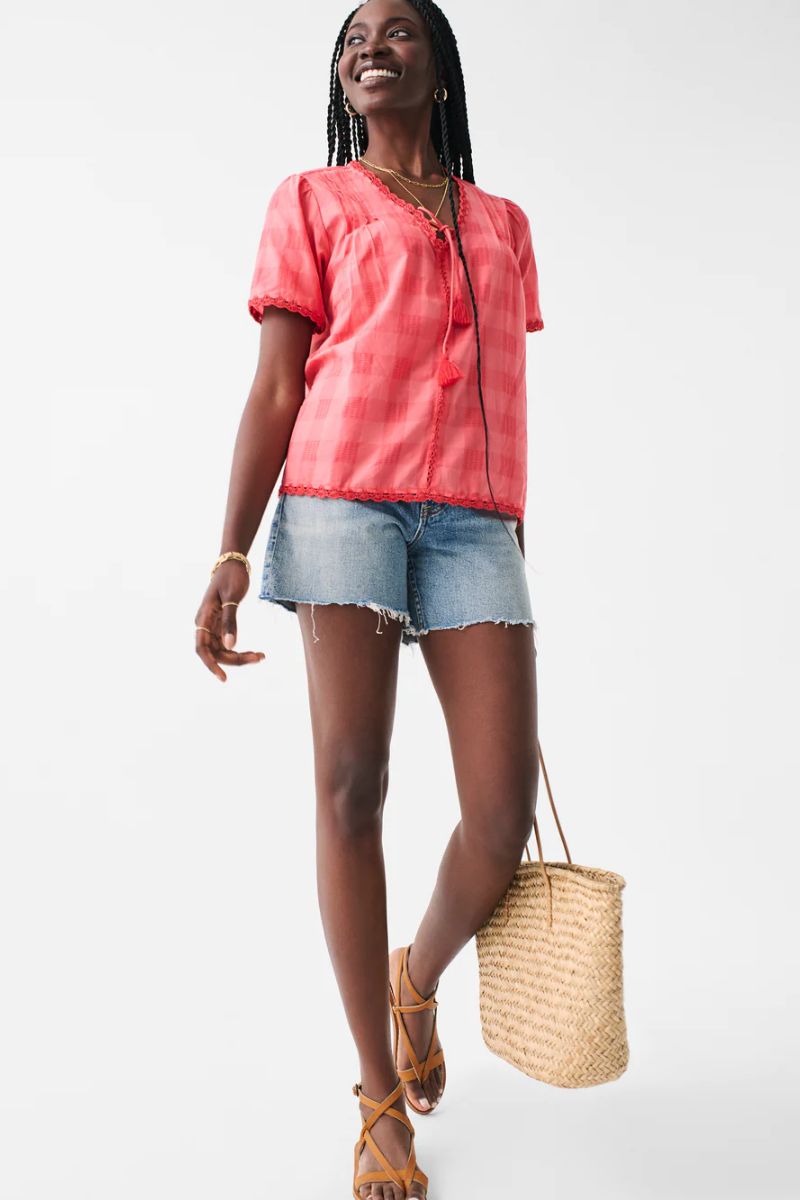 Model wears bright magenta top with crochet details.