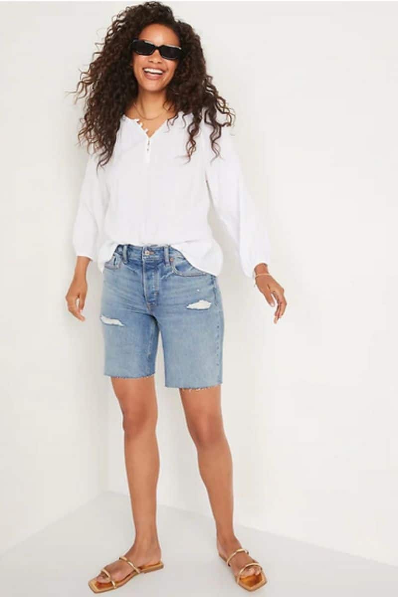 Smiling person wearing distressed denim shorts, part of the Old Navy summer clothes collection.
