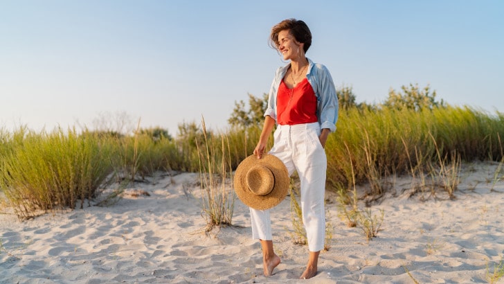 Stylish woman standing on beach.