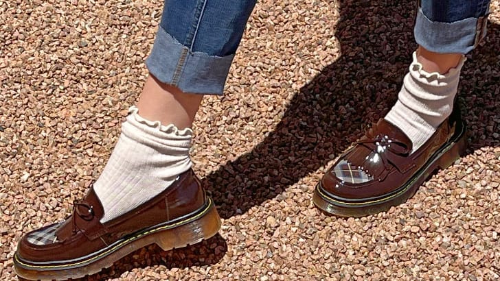 Close up view of chunky loafers with socks and ankle jeans.