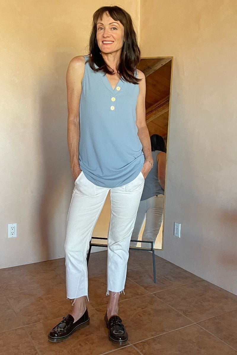 Catherine Brock kombiniert klobige Slipper mit weißen Jeanshosen und einer Tunika.