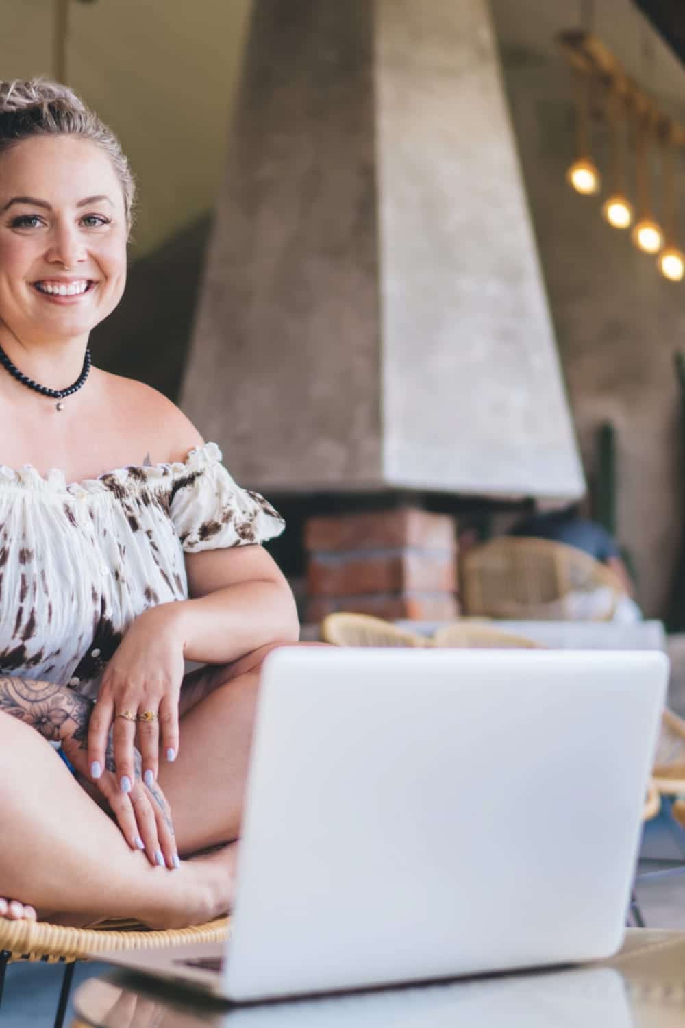 Smiling, trendy woman uses laptop to shop best online women's clothing stores.