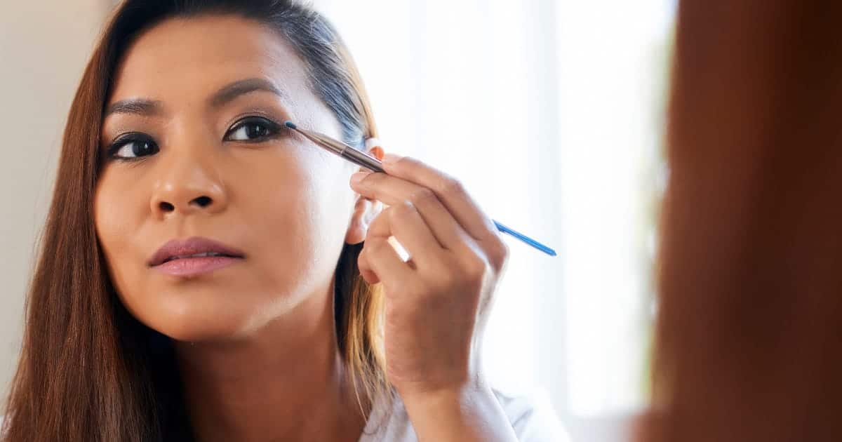 Woman applies eyeshadow with pencil brush.