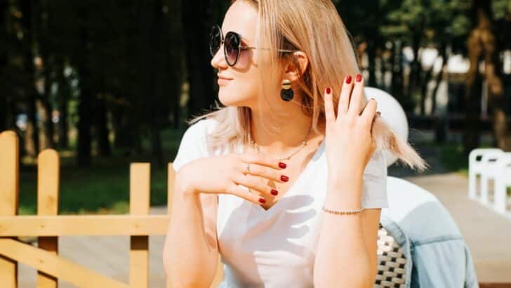 Woman sitting outside with pretty red manicure.