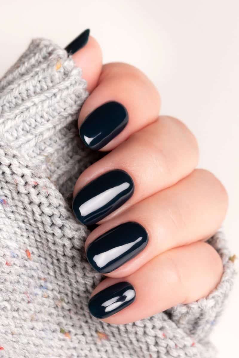 Look Rich on a Budget: 9 Pieces to Shop Now 3 Woman's hand with dark-colored gel manicure.