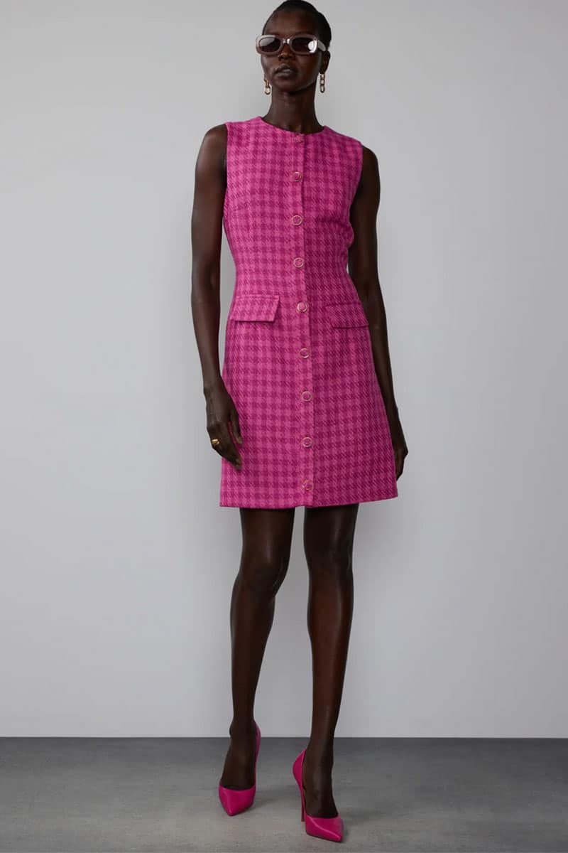Model wears pink shift dress with pink heeled shoes. 