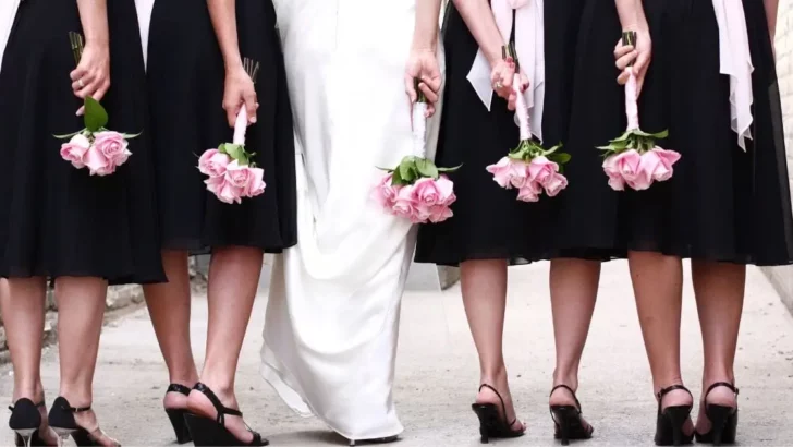View from behind of bridal party wearing black dresses and bride.