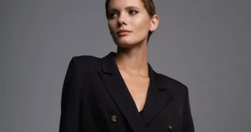 Woman wearing black blazer against gray background.