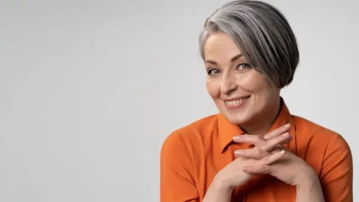 Smiling older woman wearing orange sweater.